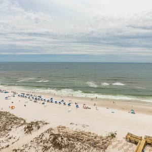 Gaze from the balcony across the gulf as gentle waves lap the shore and umbrellas dot the sand