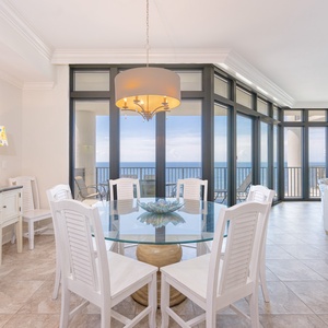 Bright dining area and a stunning coastal view through floor-to-ceiling windows