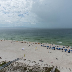 Expansive beachfront view showcasing vibrant umbrellas and sunbathers on the soft white sand, inviting relaxation and fun