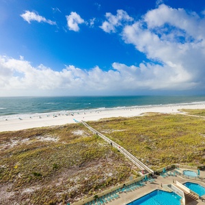 Stunning view of the beach with soft white sand, inviting turquoise waters, and a winding path leading to the shore
