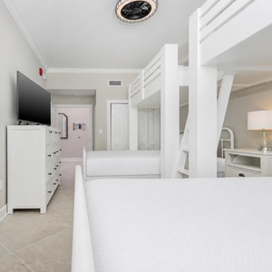Unwind with a movie in this cozy bunk room with a fun ceiling fan and two twins lofted above two queen beds