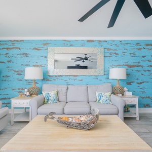 The living area features a light gray sofa, vibrant blue accent wall, and coastal decor, creating a refreshing atmosphere