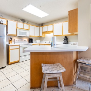 Prepare meals in the spacious kitchen, featuring stainless and white appliances and a convenient breakfast bar