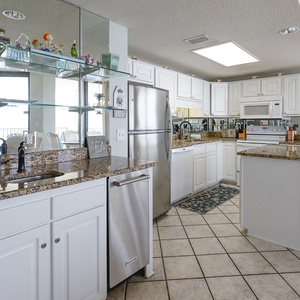 Elegant glassware displays coastal decor and an ice maker adorn this kitchen area wet bar