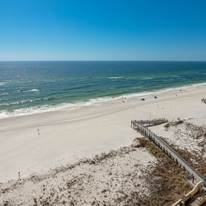 Expansive view of a serene beach with white sand and gentle waves under a clear blue sky, inviting relaxation and exploration