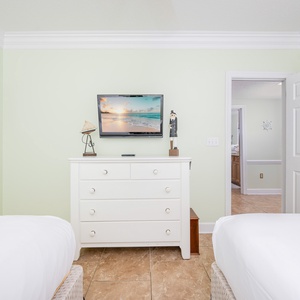 Relax in this guest bedroom featuring two double beds, coastal decor, and a TV for your entertainment