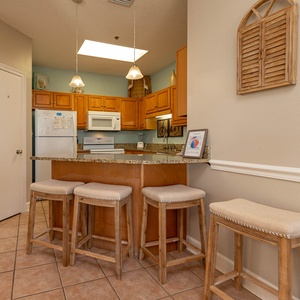 Warm wooden cabinetry complements the granite breakfast bar with seating, creating a welcoming space for meals and gatherings