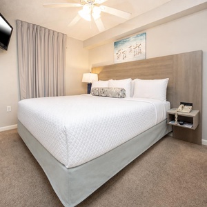 Rest comfortably in this inviting king suite featuring a plush bed, soft lighting, and a mounted TV for entertainment