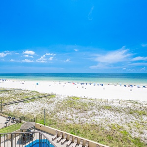 The vibrant beach front features white sand and colorful umbrellas under a clear blue sky, perfect for a relaxing getaway