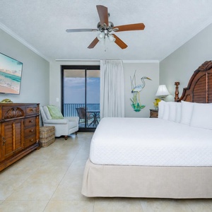 Relax in this inviting master suite featuring a king bed, coastal decor, and a balcony with beachfront access