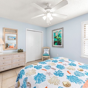 Guest bedroom featuring a queen bed, light blue walls, and coastal decor with a ceiling fan
