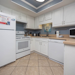 Inviting kitchen featuring white cabinetry, stainless appliances, and cheerful beach-themed decor
