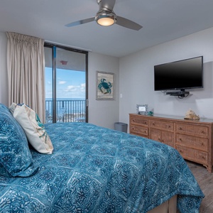 Inviting master suite featuring a king bed, coastal decor, and a balcony with beautiful beach views