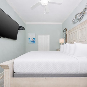 Tranquil guest bedroom featuring a king bed, a large TV, and coastal decor for a restful stay