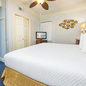 A restful king suite beckons with bright white bedding and a playful fish wall sculpture nearby