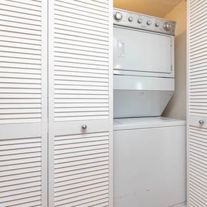 Convenient laundry area featuring a stacked washer and dryer behind stylish louvered doors for easy access