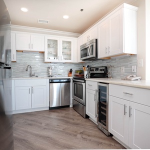 White cabinetry and marbled countertops enhance this kitchen, featuring a breakfast bar and modern appliances