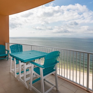 Breathe gulf air on the balcony while seated in blue Adirondack chairs, watching the shore