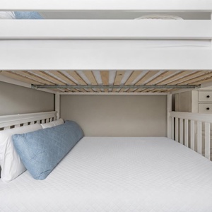 Spacious queen bunk bed with a soft blue accent pillow, perfect for family getaways or kids' adventures in a welcoming space