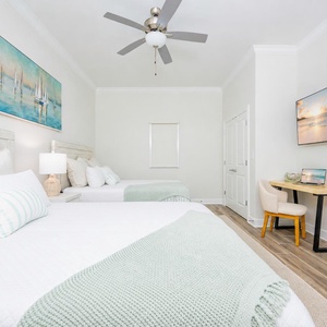 Relax in this guest bedroom featuring two queen beds, a stylish desk, and soothing decor for a restful stay