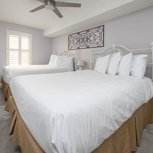 Guest bedroom featuring two queen beds with plush bedding and a decorative wall piece