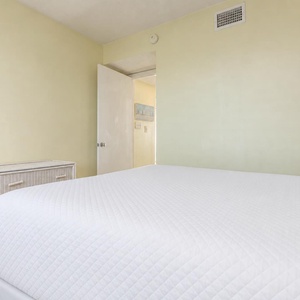 This cozy bedroom features a queen bed, soft yellow walls, and a welcoming atmosphere for a restful stay