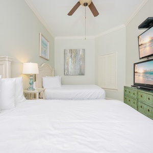 Guest bedroom featuring two queen beds, a stylish green dresser, and dual flat-screen TVs for entertainment
