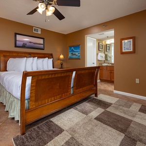 Master bedroom featuring a wooden bed with plush white linens, a stylish nightstand, and an adjoining bathroom visible