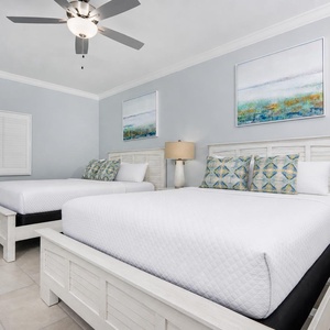 Inviting guest bedroom featuring two cozy queen beds, decorative pillows, and soothing artwork