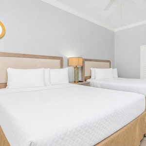 Rest comfortably in this guest bedroom featuring two queen beds, stylish lighting, and soft coastal decor