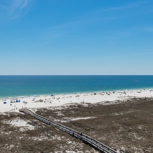 Stunning beach scene features soft white sand, colorful umbrellas, and a serene gulf view stretching under a clear blue sky