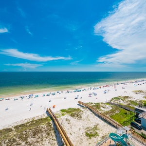 Experience the vibrant beach scene with colorful umbrellas and sunbathers along the inviting shoreline