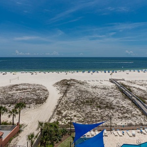 Gaze at the inviting beach, dotted with umbrellas and lounge chairs, perfect for a relaxing day in the sun