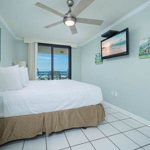 Unwind in this serene master bedroom featuring a king bed, a ceiling fan, and beachfront balcony access