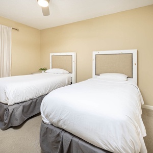 Bright guest bedroom featuring two twin beds with stylish headboards and a cozy atmosphere, perfect for restful nights