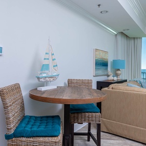 Enjoy the morning at the round breakfast table with cozy cushioned chairs, complemented by beach decor and natural light