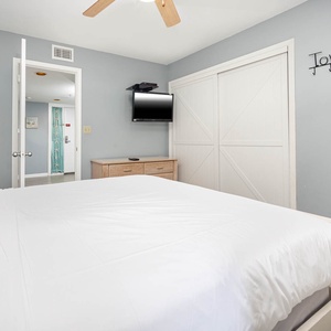 This cozy bedroom features a comfortable queen bed, bunks, a wall-mounted TV, and easy access to an adjoining bathroom