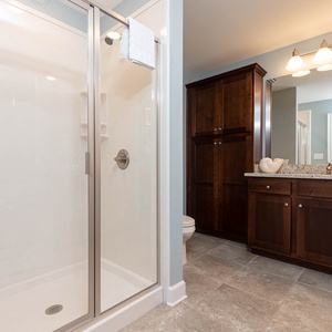 Enjoy a relaxing shower after a day at the beach in this guest bath with stylish cabinetry and spacious vanity