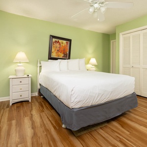 This cozy guest bedroom features soft green walls, a comfortable queen bed, and warm wood flooring