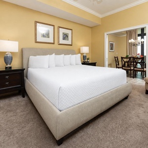 Welcoming master bedroom featuring a king bed, cozy armchair, and warm yellow walls for a relaxing stay