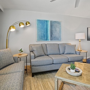 Living area featuring a cozy gray sofa, stylish blue accent chair, and modern artwork, creating a relaxed atmosphere