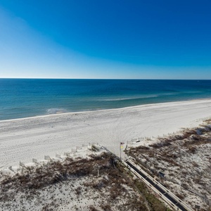 Gaze at the tranquil shoreline and clear blue waters, perfect for relaxation and beachside strolls