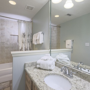 Master bath featuring a tub/shower combo, granite countertops, and neatly arranged towels for a refreshing stay