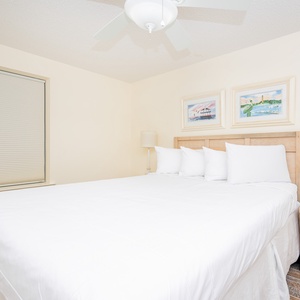 Relax in this comfortable guest bedroom featuring a queen bed, coastal art, and soft lighting
