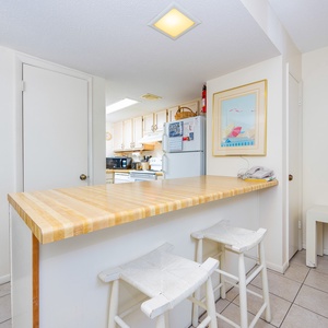 The kitchen features a wooden breakfast bar, white cabinetry, and a cozy seating area, perfect for casual dining