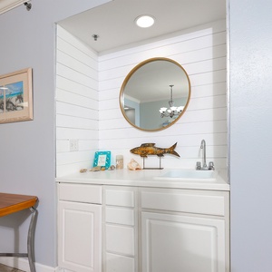 This charming wet bar features a stylish round mirror and decorative accents, perfect for entertaining guests