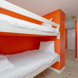 This cozy nook features built-in bunk beds against vibrant red walls, leading to a relaxing view of the beachfront