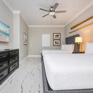 Rest in this cozy guest room featuring two queen beds, a large TV, and tasteful decor for a relaxing getaway