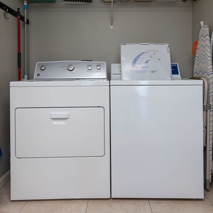 Laundry area featuring a washer and dryer, with an ironing board and storage space for convenience during your stay