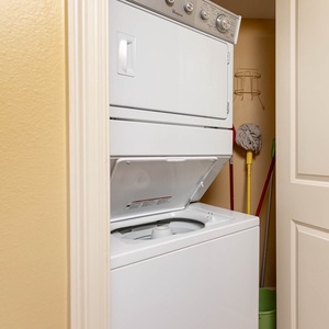 Washer and dryer combo tucked in a closet, with cleaning supplies neatly arranged nearby for convenience during your stay